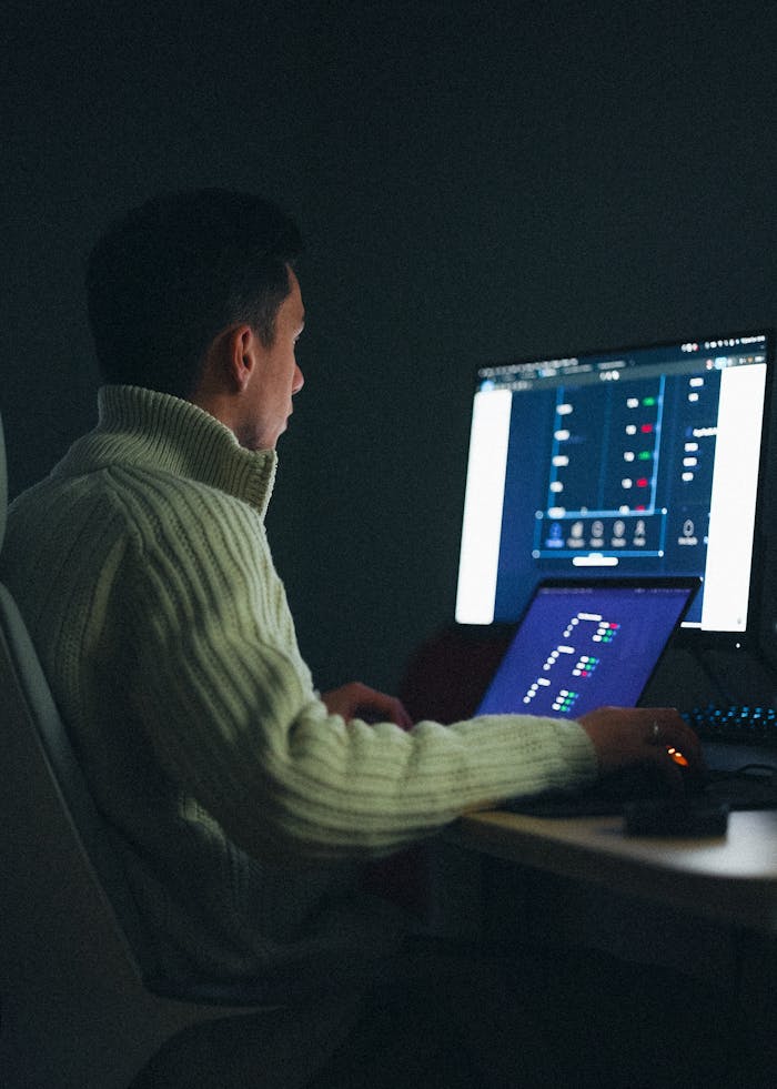 Adult male working on a computer at night in a dark room.
